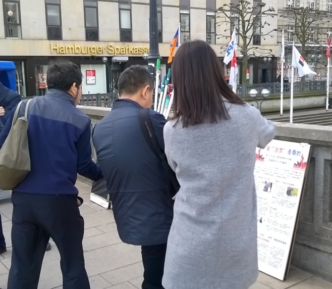 Tiga pengunjung dari Tiongkok mengambil foto tentang informasi Falun Gong